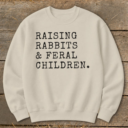 Cream sweatshirt with black text: Raising Rabbits & Feral Children.