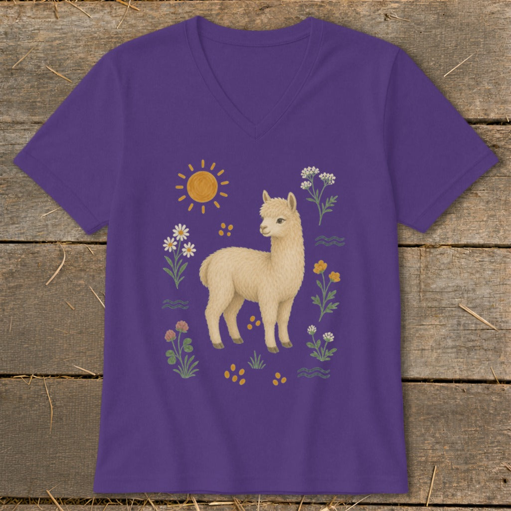 Purple t-shirt with a cream alpaca surrounded by flowers, sun, and yellow dots.