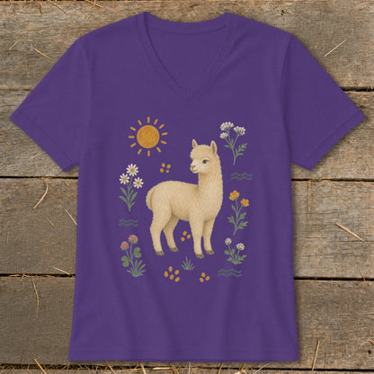 Purple t-shirt with a cream alpaca surrounded by flowers, sun, and yellow dots.