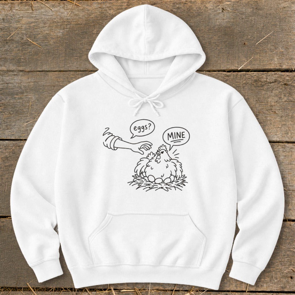 White hoodie with a black line drawing of a chicken guarding eggs, saying "MINE" to a hand asking "eggs?".