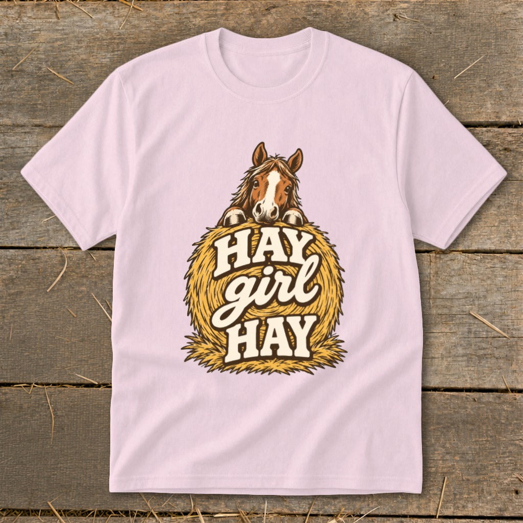 Light pink t-shirt with a horse peeking over a hay bale that says "Hay girl HAY".