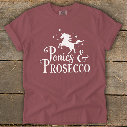 Maroon t-shirt with white graphic of a running horse and "Ponies & Prosecco" text.