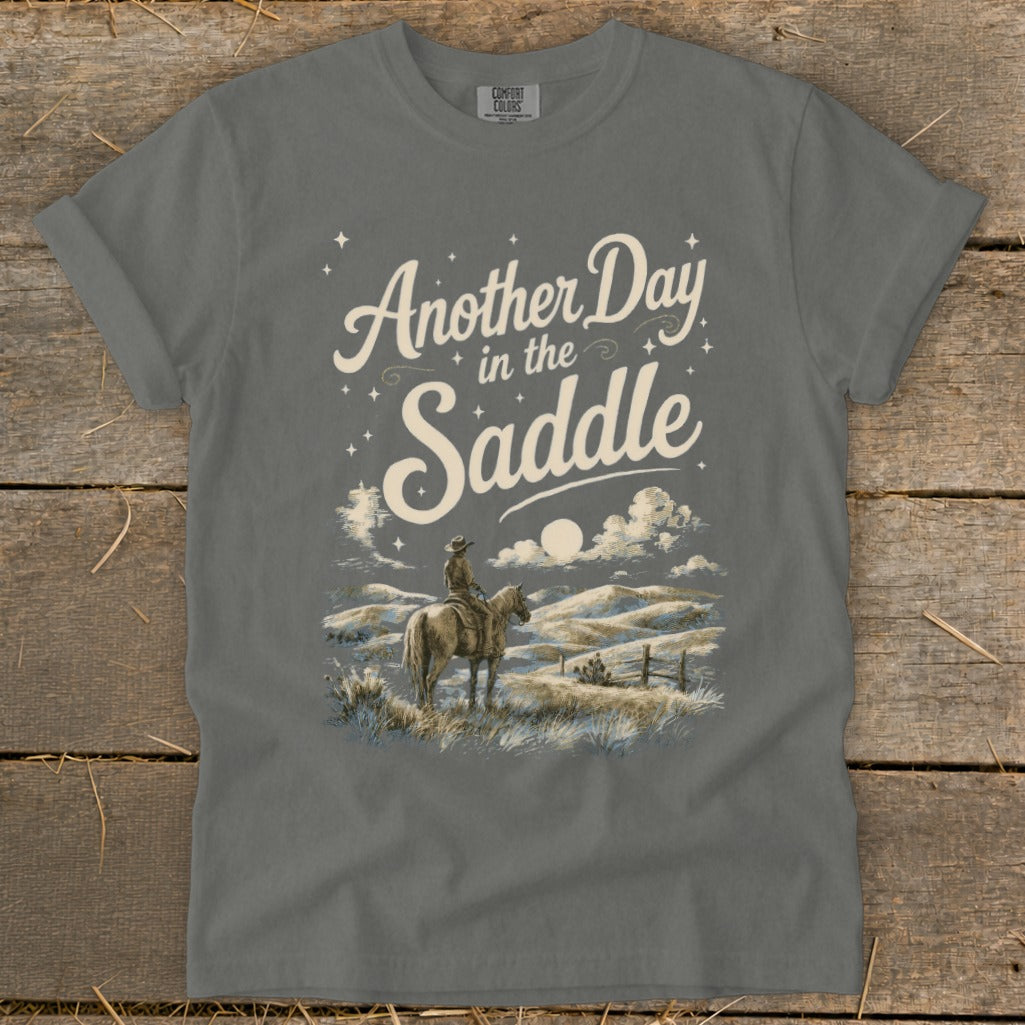 Grey t-shirt with "Another Day in the Saddle" text and a cowboy on horseback.