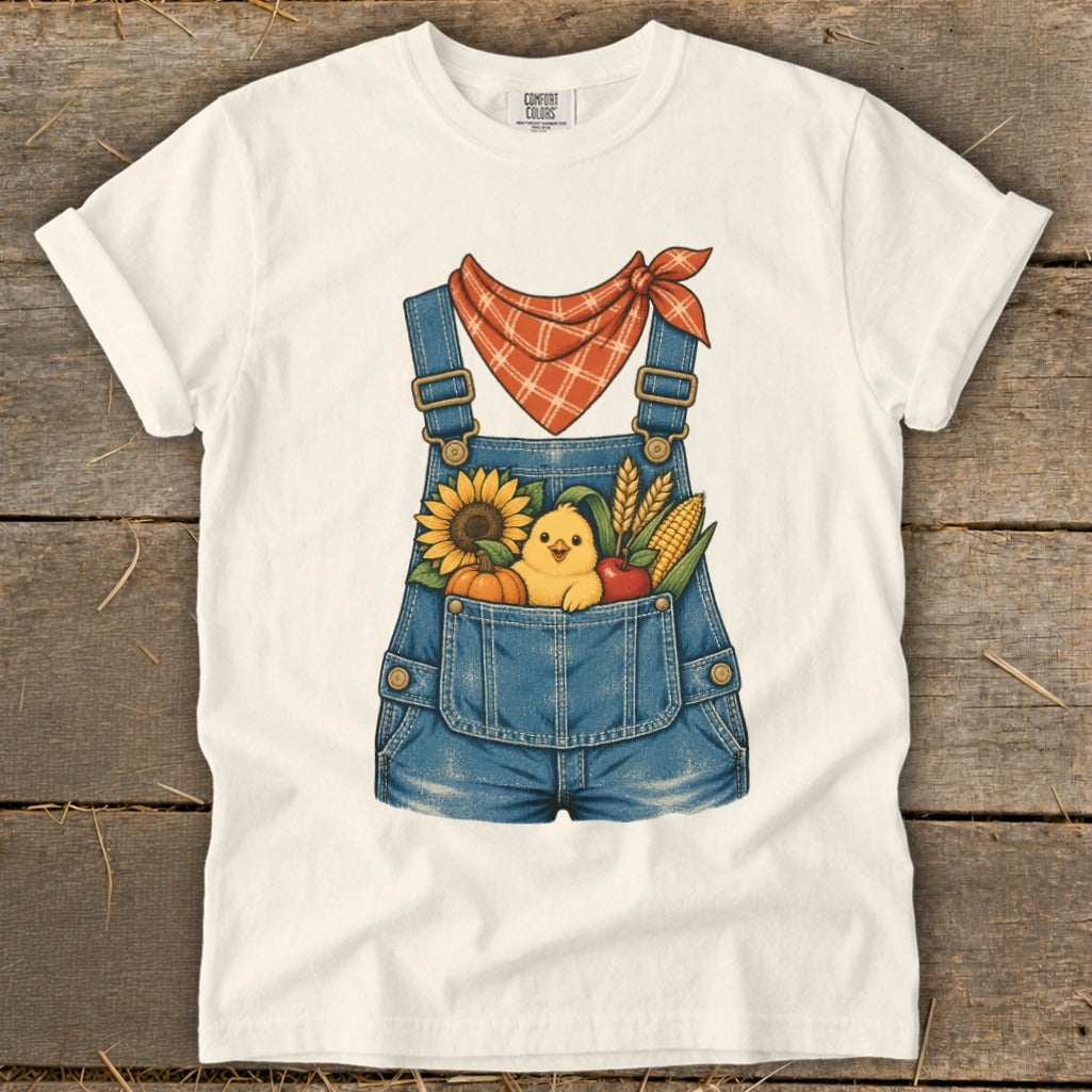 White t-shirt with denim overalls graphic featuring a chick and autumn harvest items.