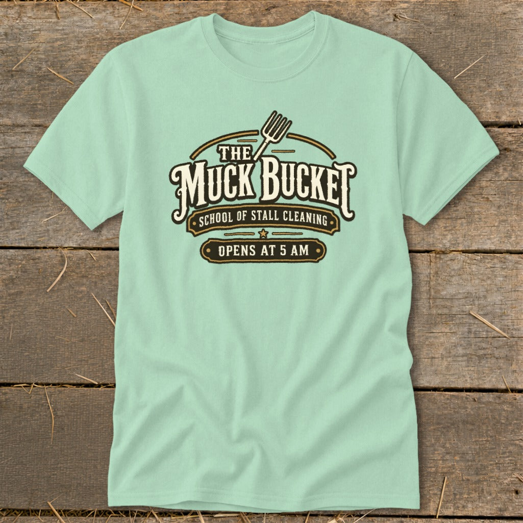 Light green t-shirt with "The Muck Bucket School of Stall Cleaning Opens at 5 AM" graphic.