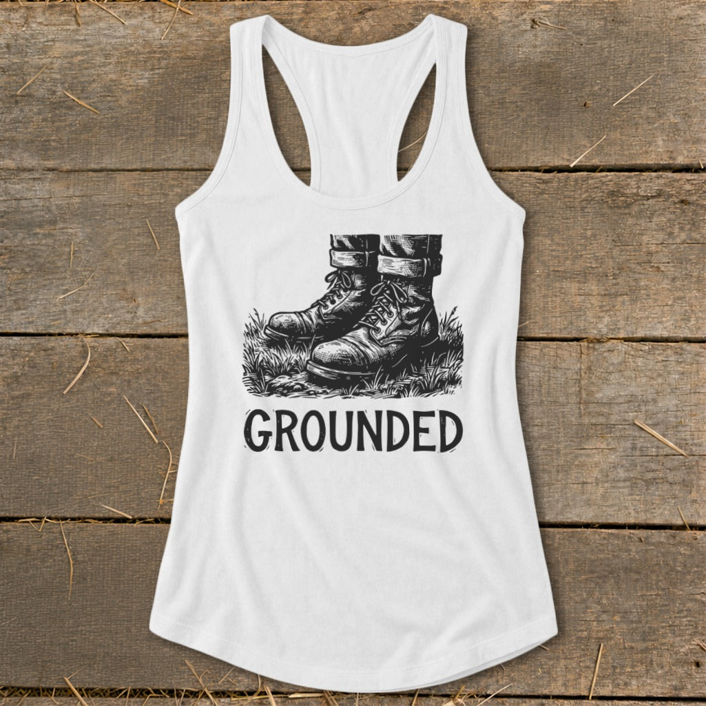 White tank top with black ink drawing of boots standing in grass, text "GROUNDED".