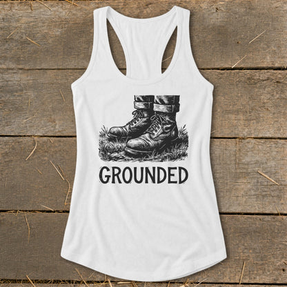 White tank top with black ink drawing of boots standing in grass, text "GROUNDED".