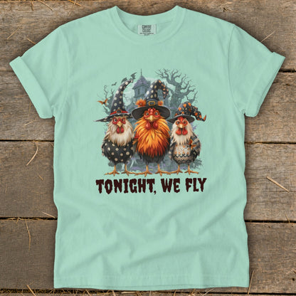Three chickens wearing witch hats stand before a spooky house, with text "TONIGHT, WE FLY".