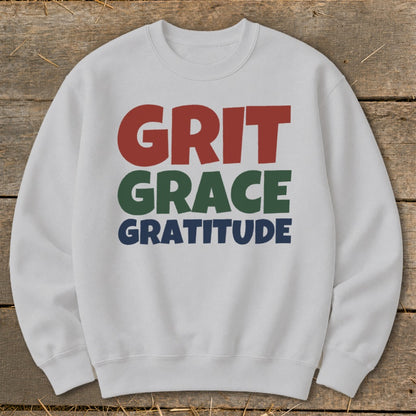 Light gray crewneck sweatshirt featuring the words GRIT in red, GRACE in green, and GRATITUDE in blue.