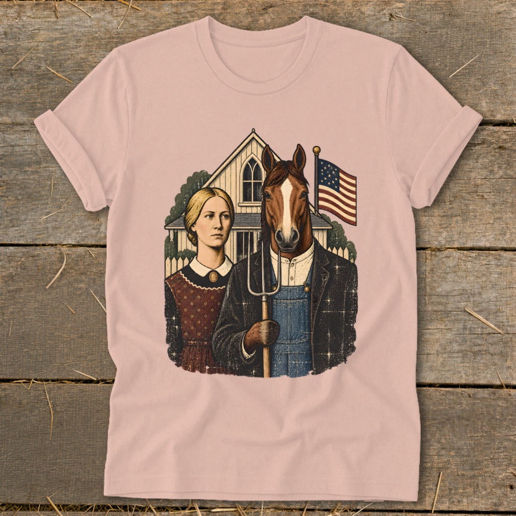 A pastel pink t-shirt featuring a parody American Gothic graphic with a human-horse hybrid holding a pitchfork.