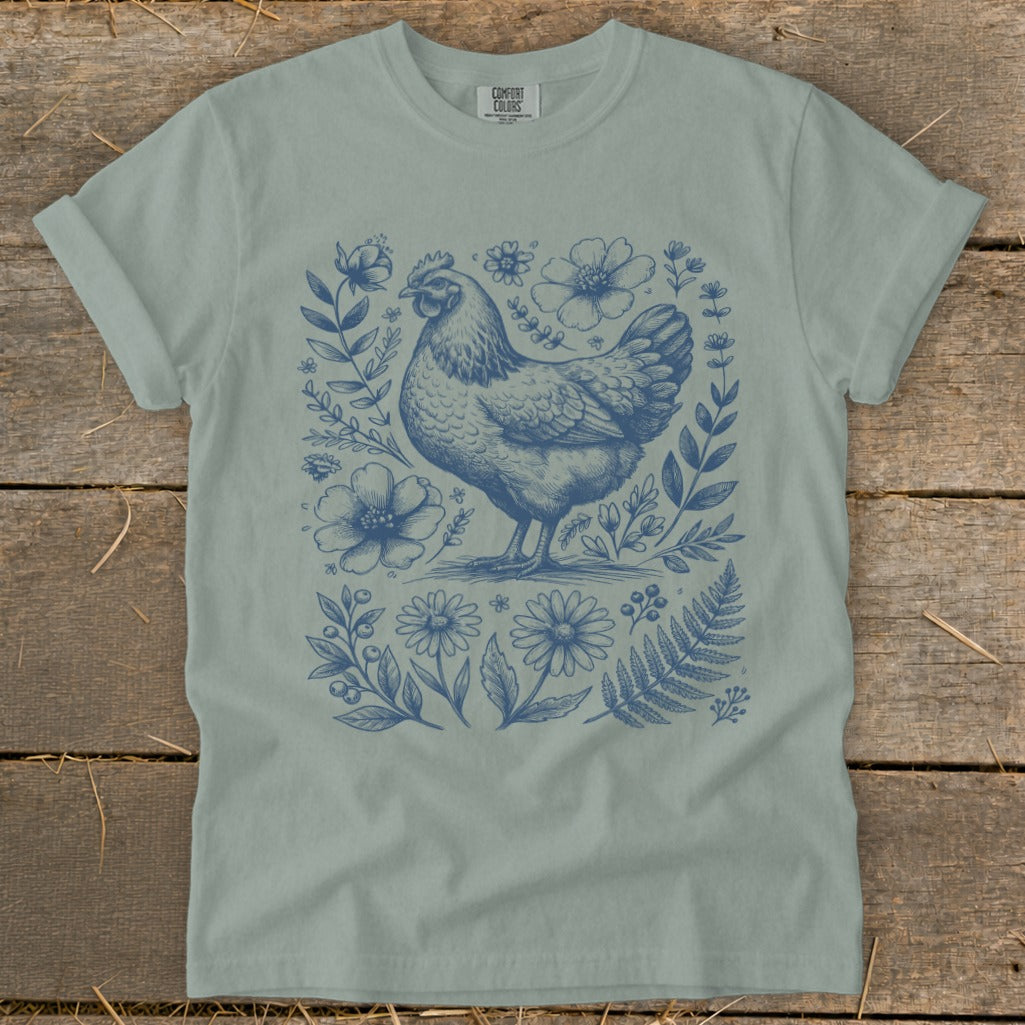 Blue chicken and floral illustration on a light sage green Comfort Colors t-shirt.