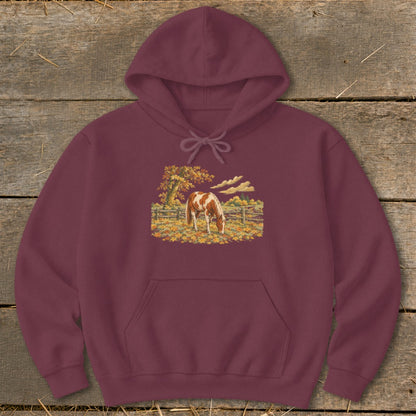 Maroon hoodie with a brown and white horse grazing in a fall landscape.