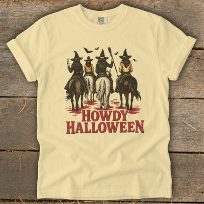 Light yellow t-shirt with three witches on horseback and "Howdy Halloween" text.