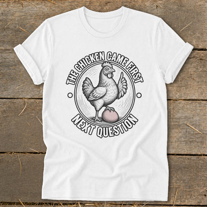 White t-shirt with a chicken and egg graphic and text "The chicken came first, next question".