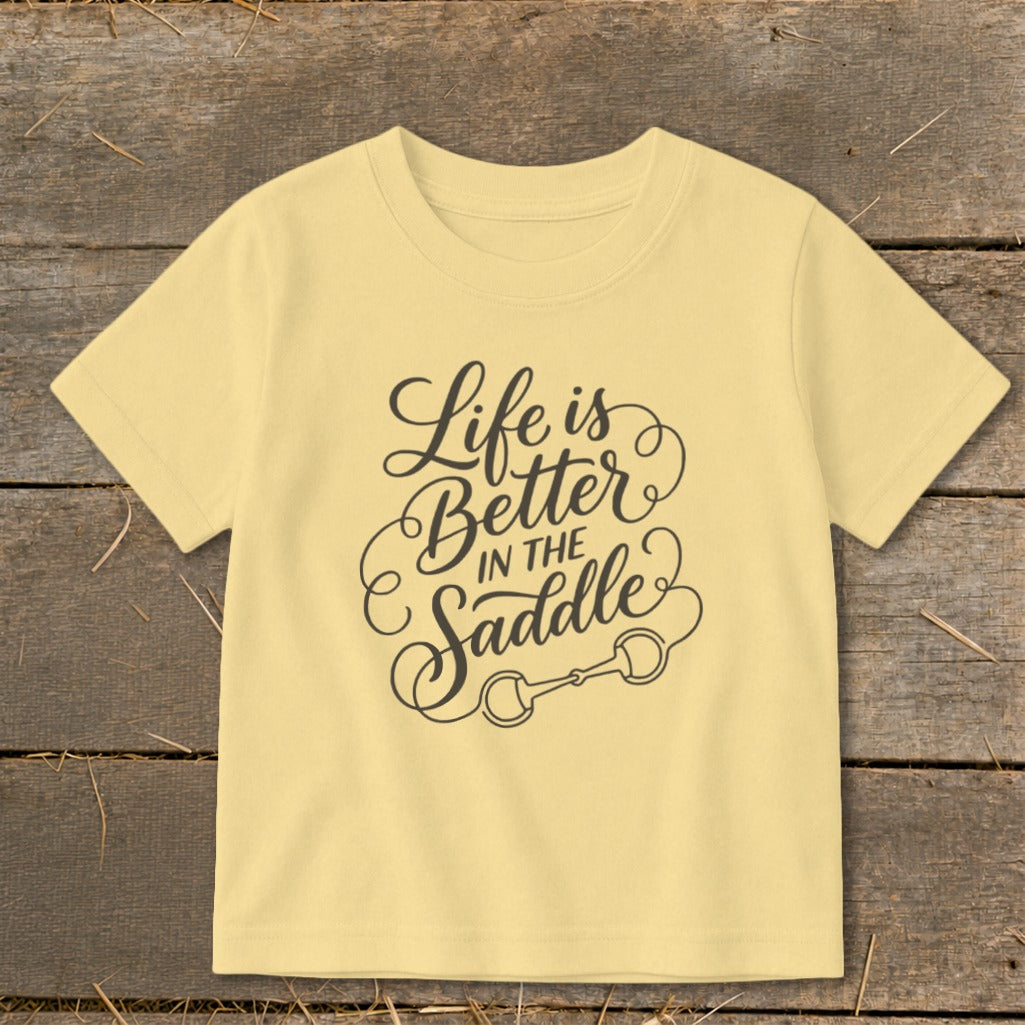 Yellow t-shirt with "Life is Better in the Saddle" text and horse bit graphic.
