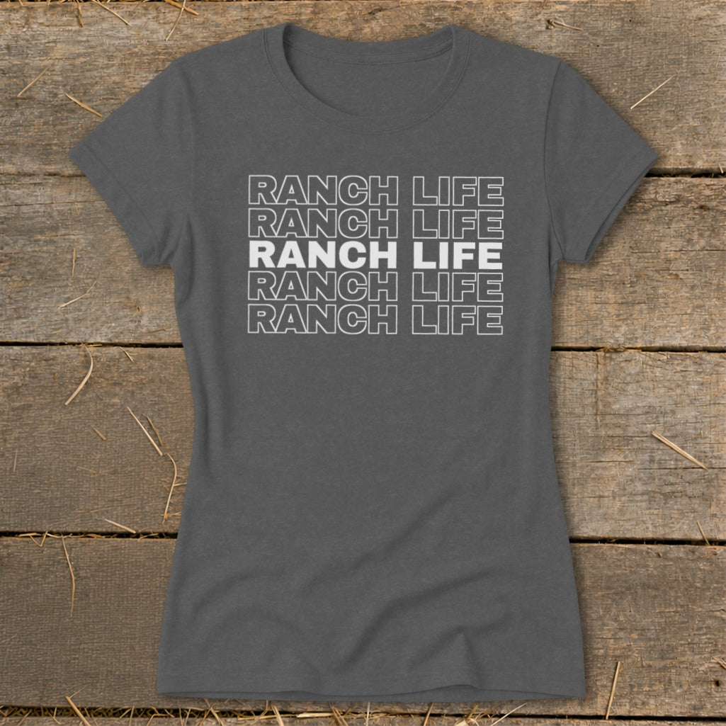 Dark gray women's t-shirt featuring stacked white text that reads RANCH LIFE on a rustic wooden background.