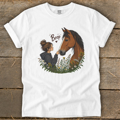 Illustration of a girl booping a horse's nose surrounded by flowers.