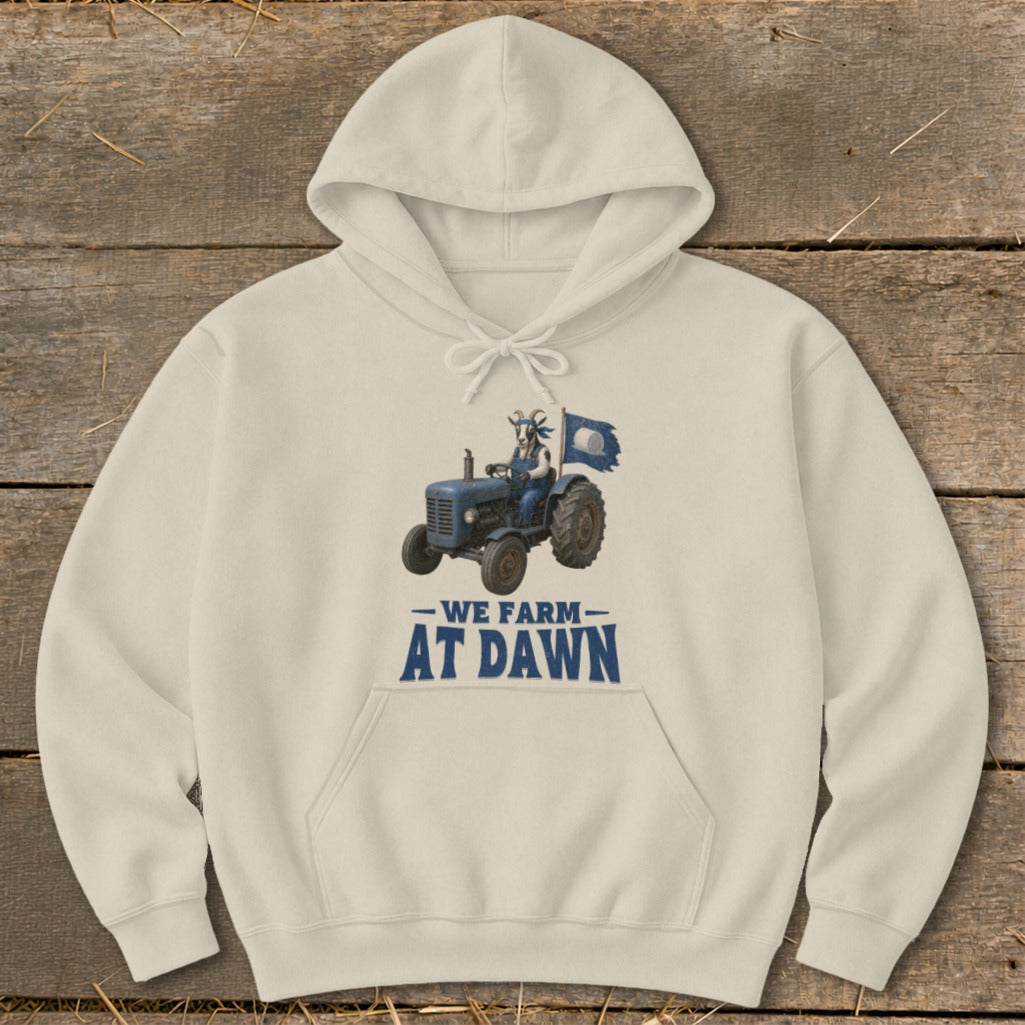 Cream hoodie with graphic of goat driving tractor, reading "We Farm At Dawn."