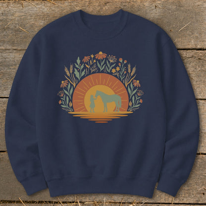 Crewneck sweatshirt with a sunset graphic featuring a person and a horse surrounded by floral elements.