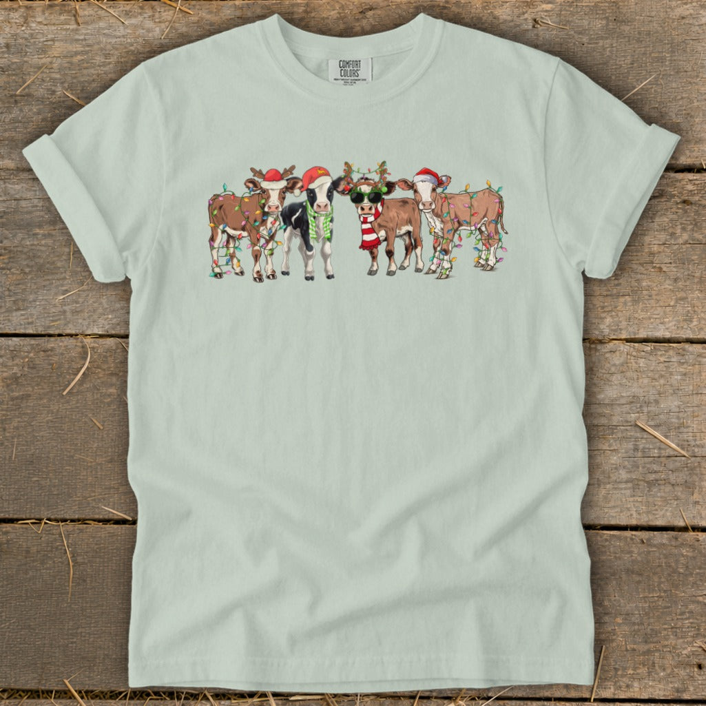Five cows wearing Christmas hats and lights, one with sunglasses and scarf.