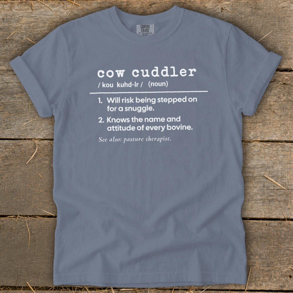 Blue t-shirt with "cow cuddler" definition, listing bravery and bovine knowledge.