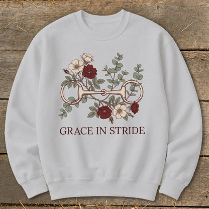 Light gray sweatshirt with a horse bit and floral graphic and text "GRACE IN STRIDE".