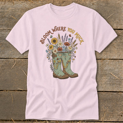Pink t-shirt with graphic of green boots overflowing with flowers and text "Bloom Where You Muck".