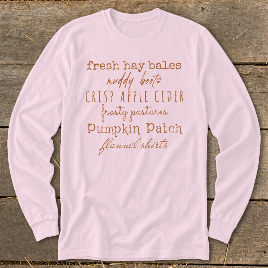 Light pink long-sleeve shirt with "fresh hay bales muddy boots crisp apple cider" text.