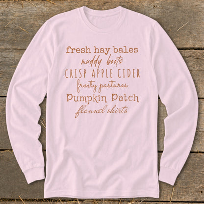 Light pink long-sleeve shirt with "fresh hay bales muddy boots crisp apple cider" text.