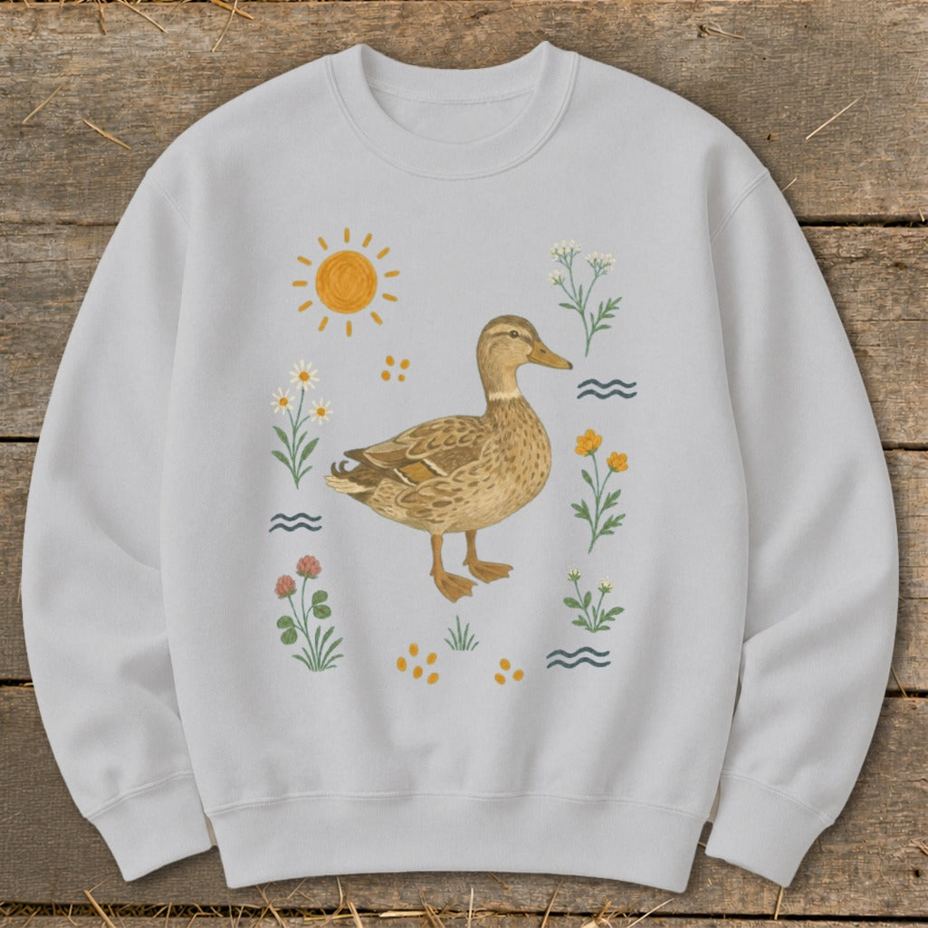 Light grey sweatshirt with a watercolor illustration of a duck surrounded by flowers and sun.