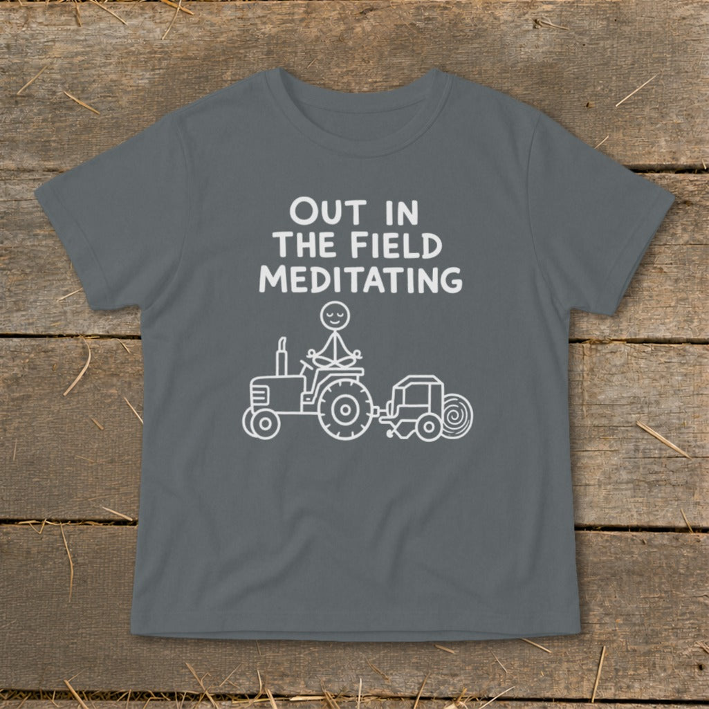T-shirt with text "OUT IN THE FIELD MEDITATING" and drawing of person meditating on a tractor.