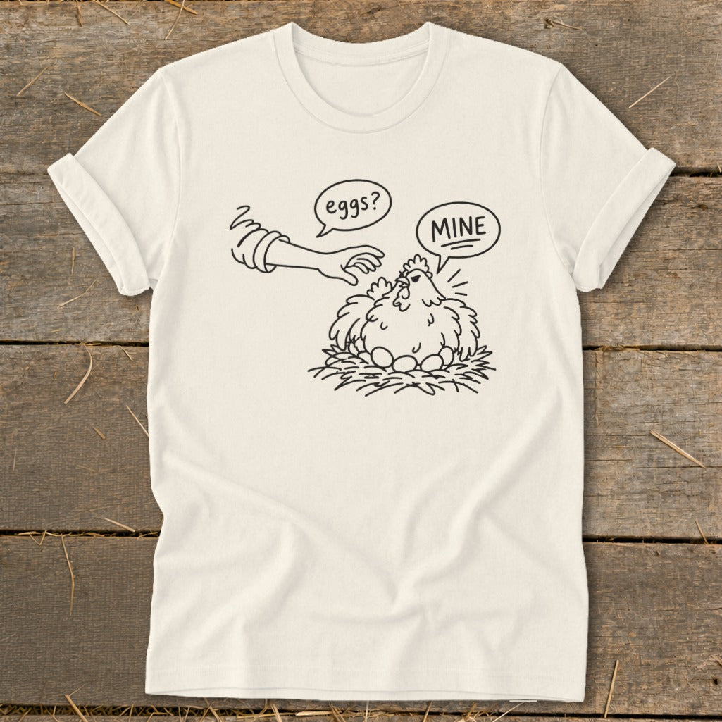 T-shirt graphic of a chicken protecting eggs, with text "eggs?" and "MINE".