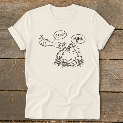 T-shirt graphic of a chicken protecting eggs, with text "eggs?" and "MINE".