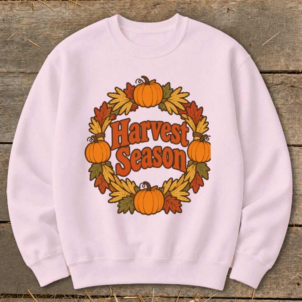 Pink crewneck sweatshirt with "Harvest Season" text in a circular wreath of pumpkins and autumn leaves.