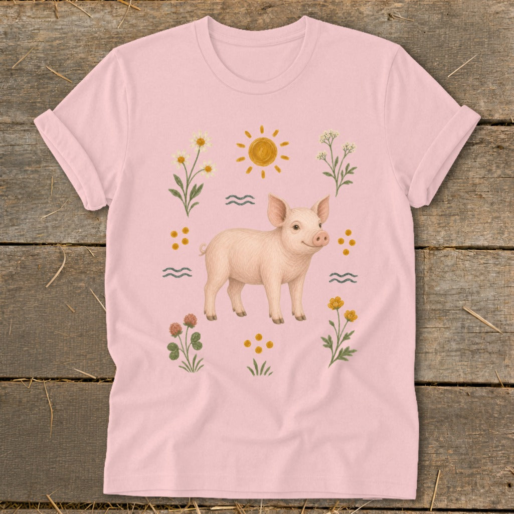 Pink t-shirt with a watercolor illustration of a pig surrounded by flowers and sun.