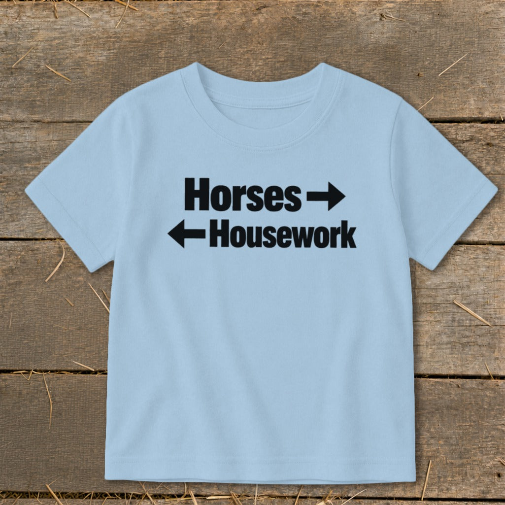 A light blue short-sleeved child's t-shirt printed with the text Horses and Housework in black.