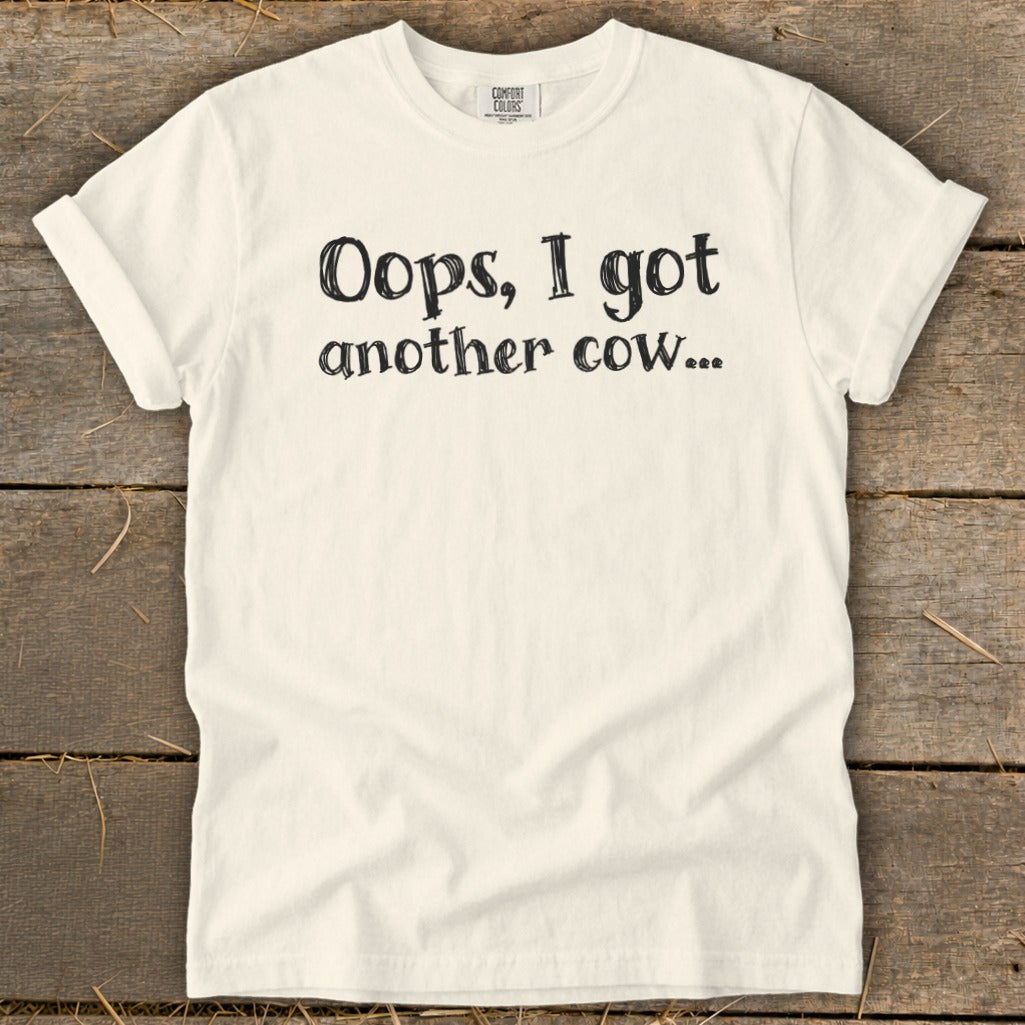 Cream t-shirt with black text "Oops, I got another cow...".