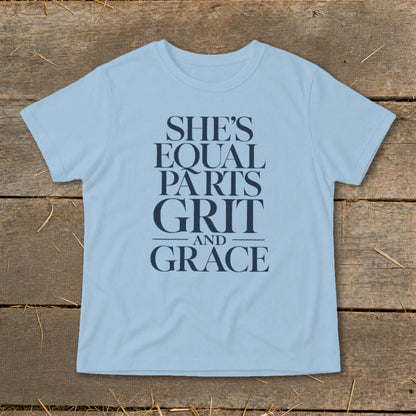 Light blue t-shirt with navy text "SHE'S EQUAL PARTS GRIT AND GRACE".