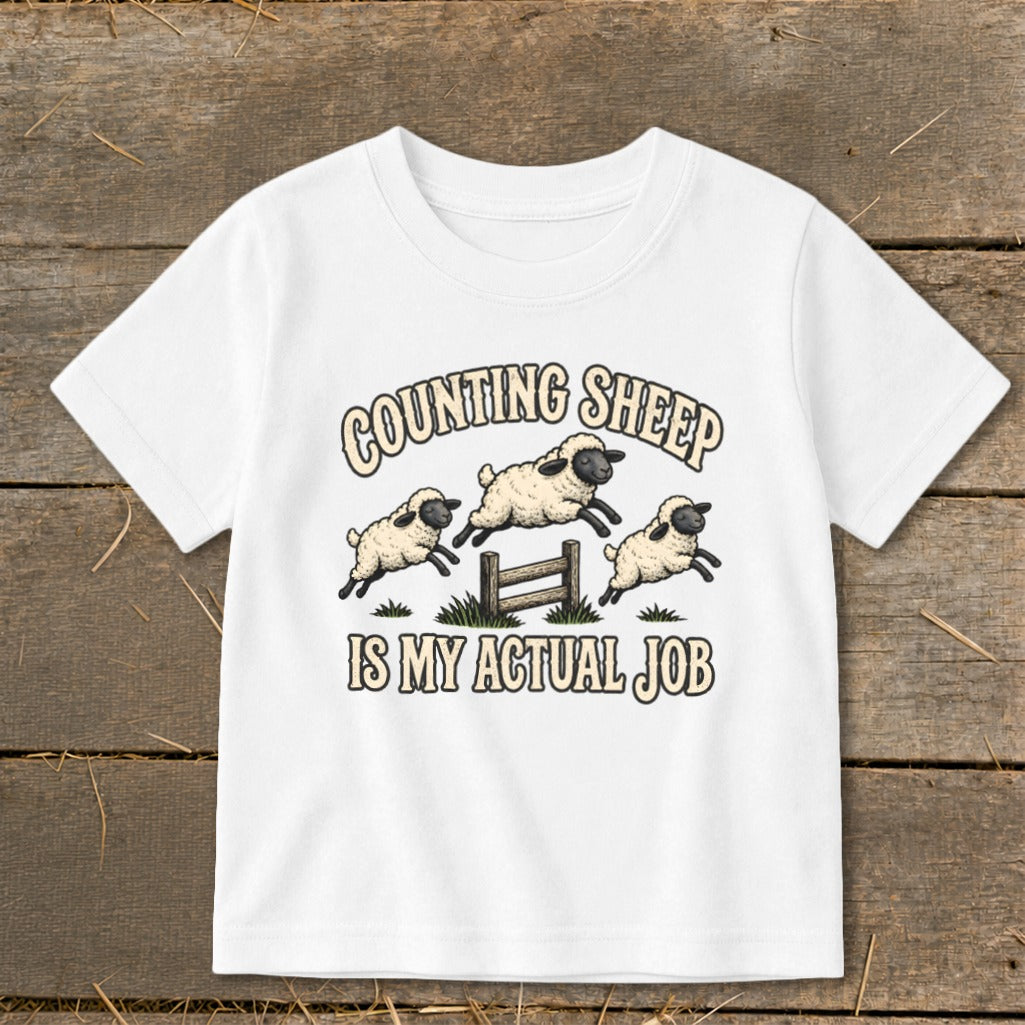 White t-shirt with graphic: "Counting Sheep Is My Actual Job" and three leaping sheep.
