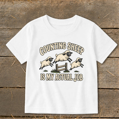 White t-shirt with graphic: "Counting Sheep Is My Actual Job" and three leaping sheep.
