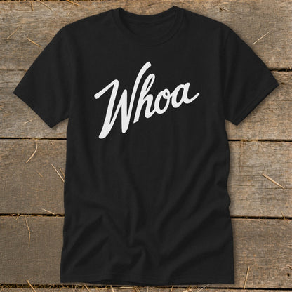 Black t-shirt with white "Whoa" script text, laid on a wooden surface.