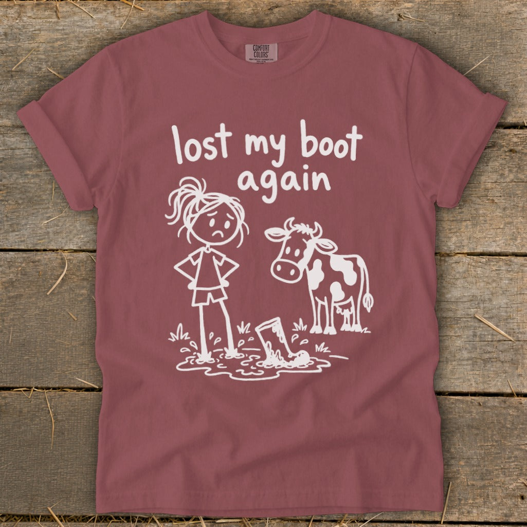 A maroon t-shirt featuring white line art of a sad person, a cow, and text reading lost my boot again.