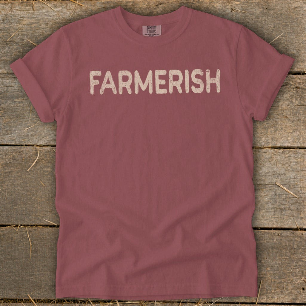 Maroon t-shirt with "FARMERISH" text in cream letters, on rustic wood background.