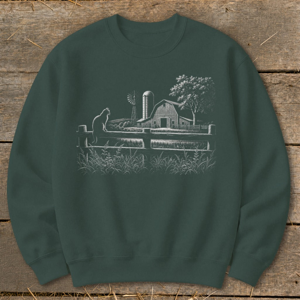 Green sweatshirt with a white line drawing of a cat on a fence, barn, windmill, and tree.