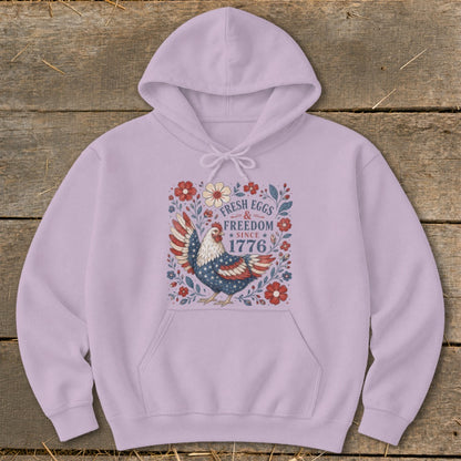 Light purple hoodie with a patriotic chicken and floral graphic reading "Fresh Eggs & Freedom Since 1776".