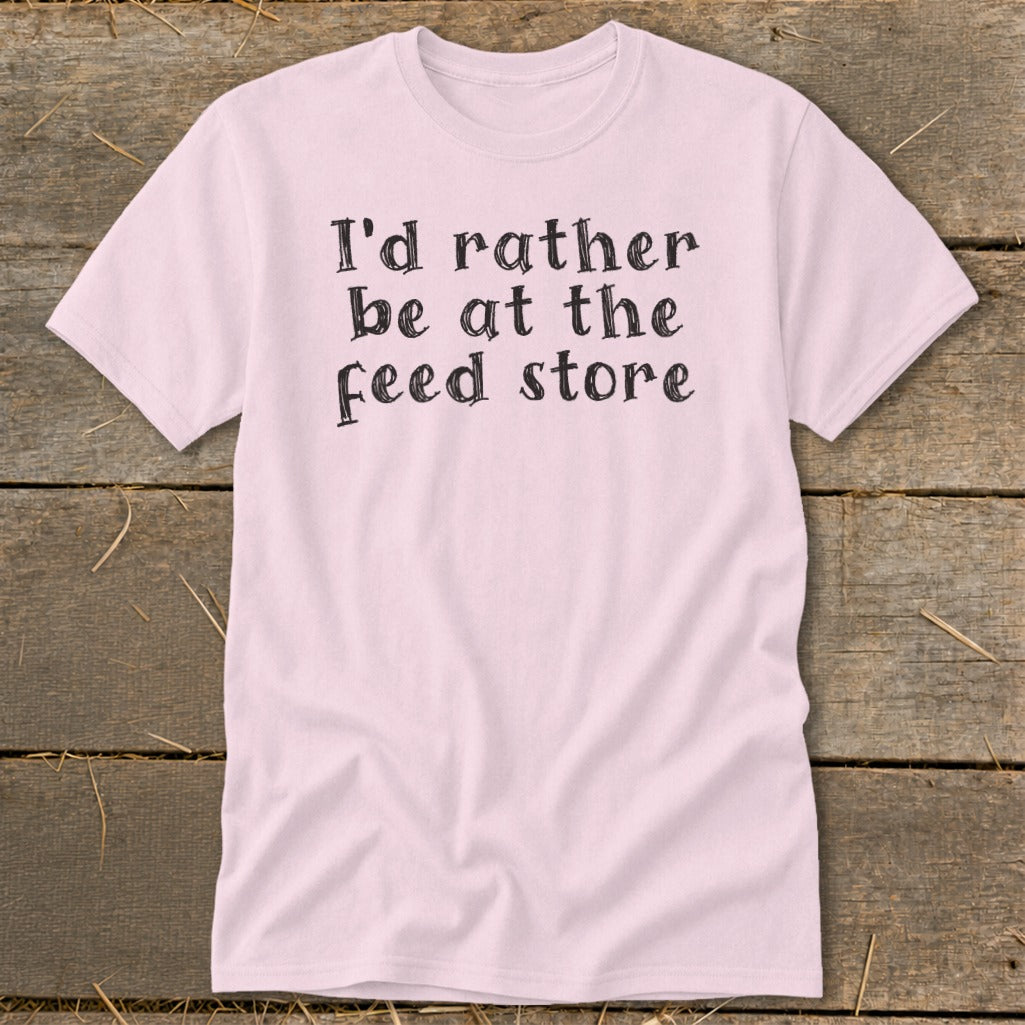 Light pink t-shirt with black text that reads "I'd rather be at the feed store."