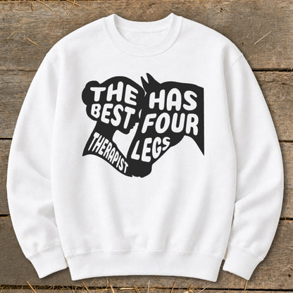 White sweatshirt with black text and horse graphic reading "THE BEST THERAPIST HAS FOUR LEGS."