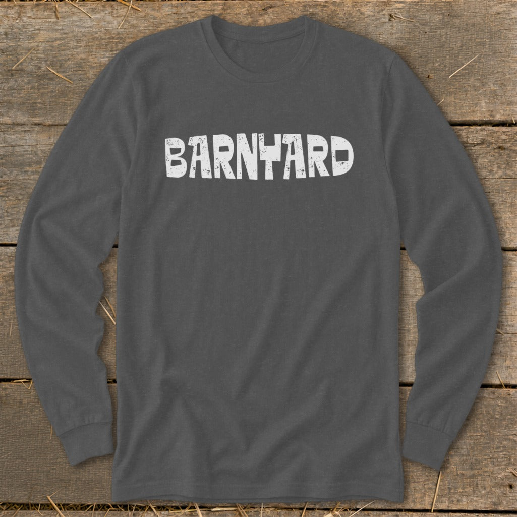 Dark gray long-sleeved crewneck t-shirt featuring the distressed white text BARNYARD centered across the chest, laid on a wooden surface.
