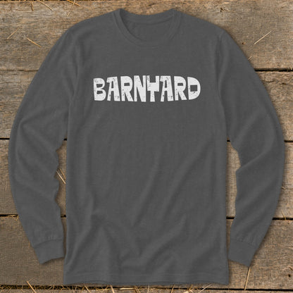 Dark gray long-sleeved crewneck t-shirt featuring the distressed white text BARNYARD centered across the chest, laid on a wooden surface.