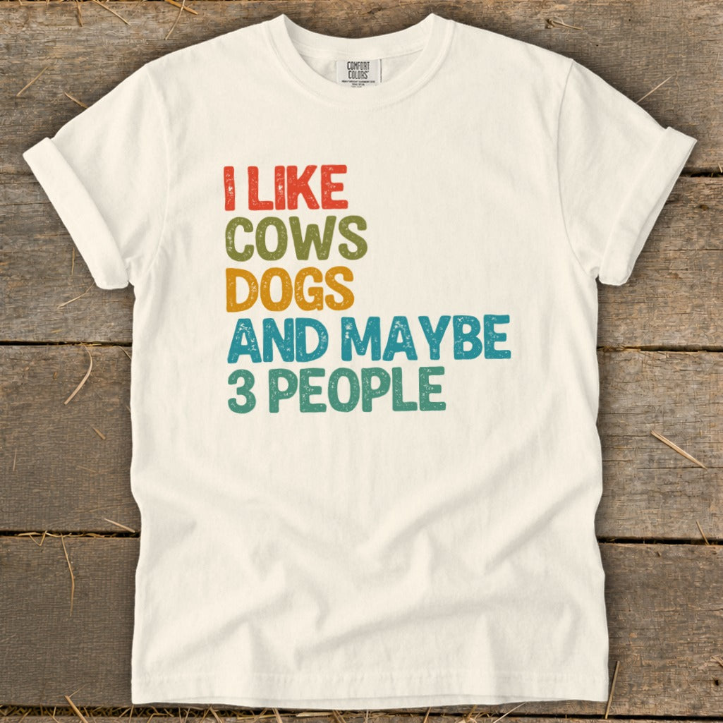 Cream Comfort Colors t-shirt with "I LIKE COWS DOGS AND MAYBE 3 PEOPLE" text.